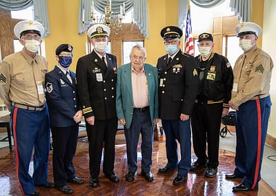 Military personnel pose with a senior veteran