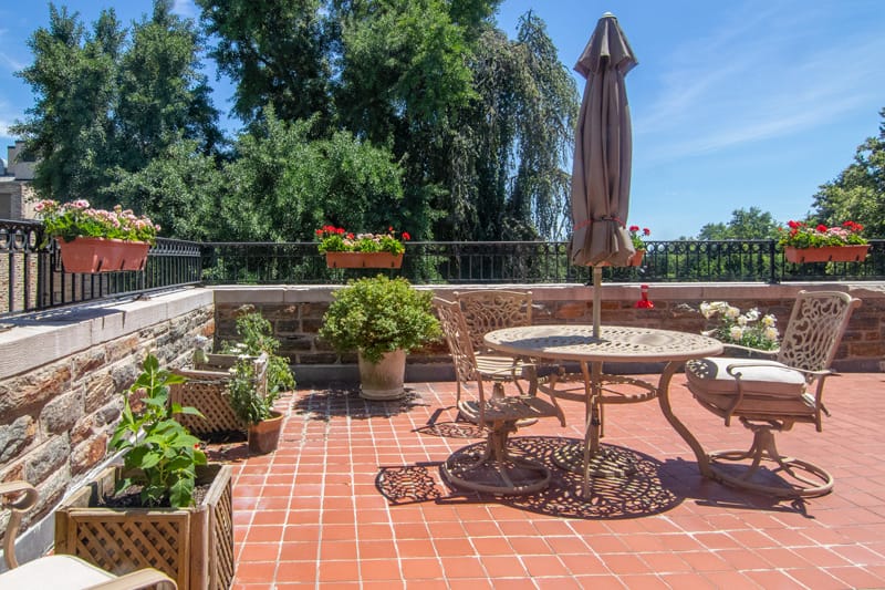Sunny view of a stone patio with a table and umbrella