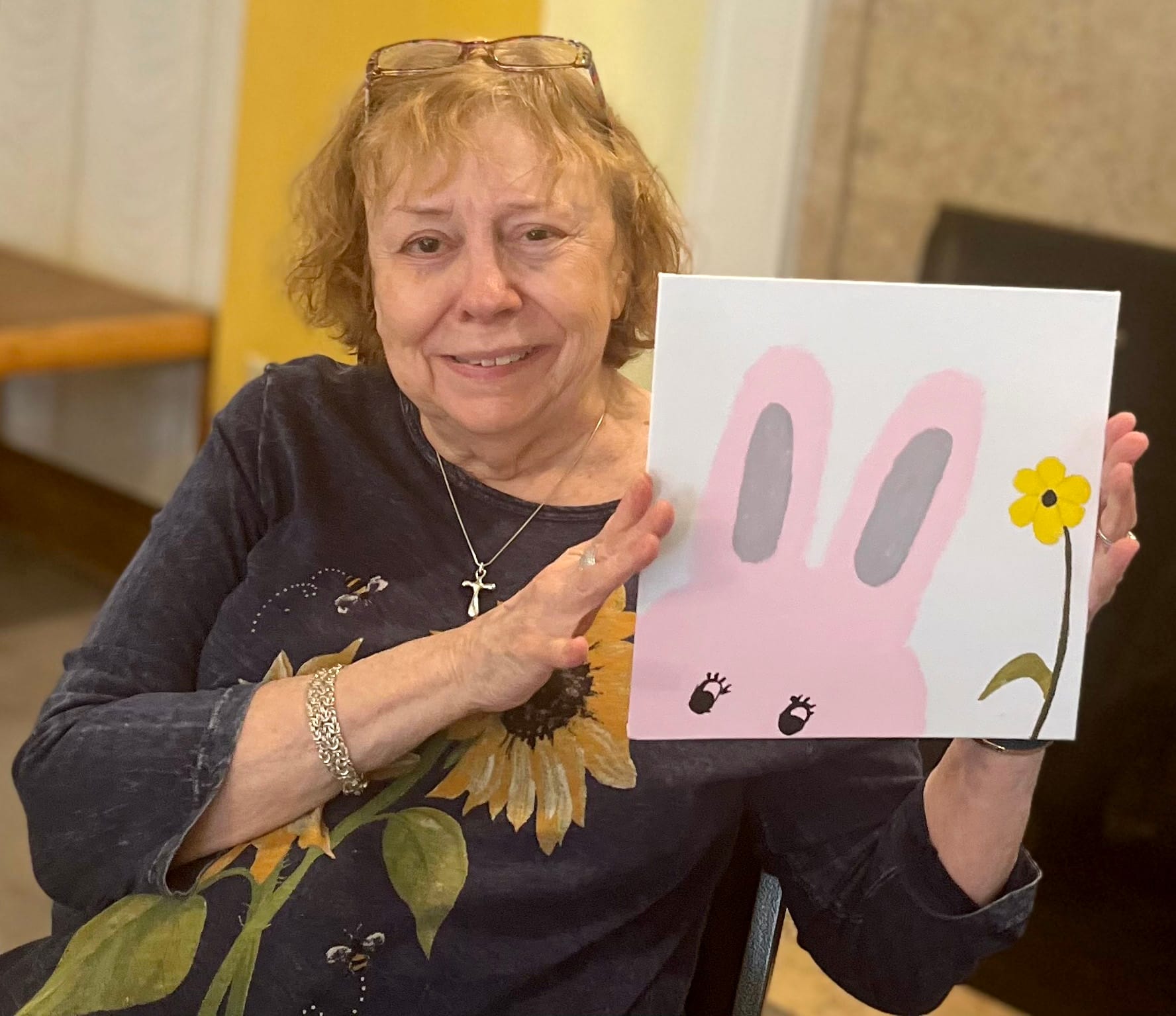 Older woman holds up her artwork